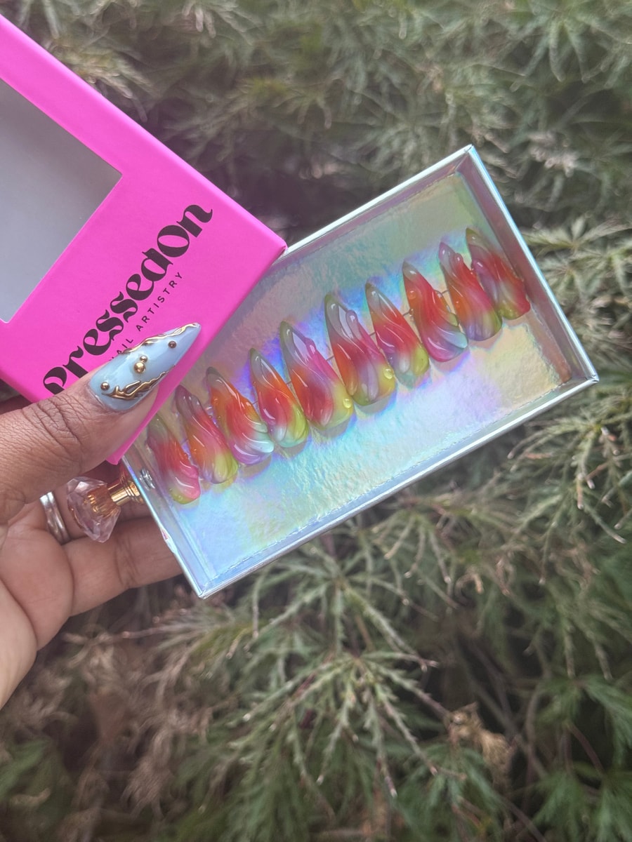 Rainbow gradient stiletto press-on nails with a transparent jelly finish in shades of red, orange, yellow, purple, and green.