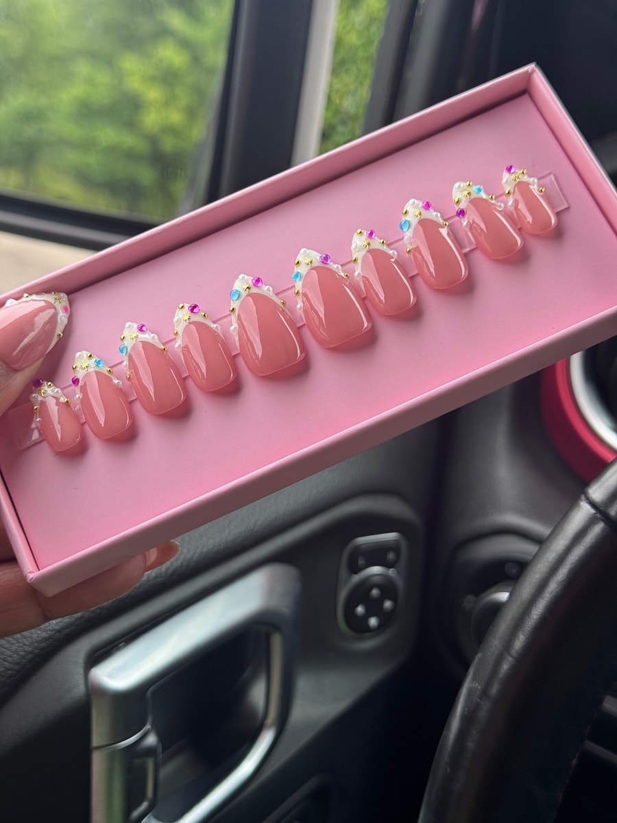 Set of super short pink press-on nails with white tips, iridescent accents, gold studs and colorful gems.