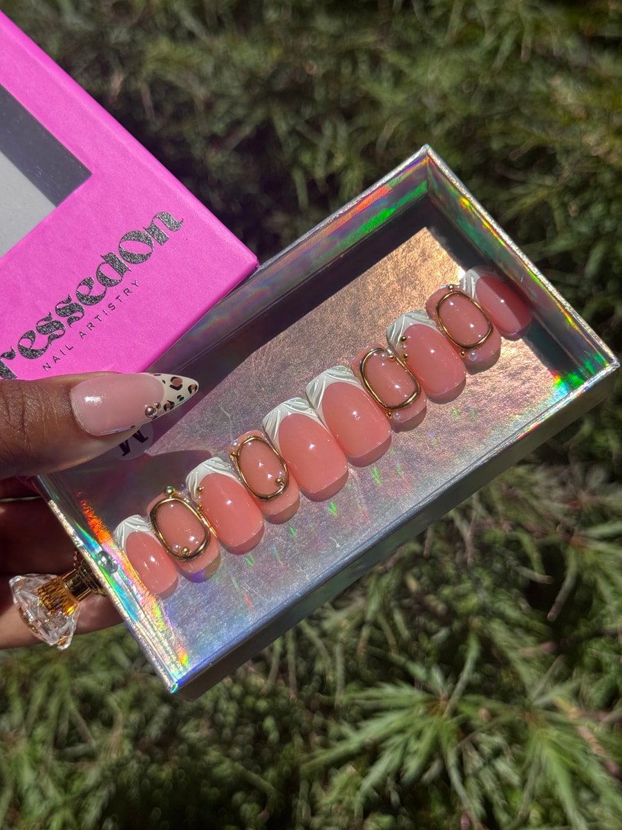 Set of super short pink press-on nails with white French tips, gold 3D oval accents, and pearl embellishments.