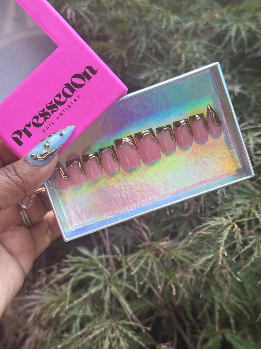Short pink press-on nails feature a gold drip design at the tips, offering a chic and modern look.