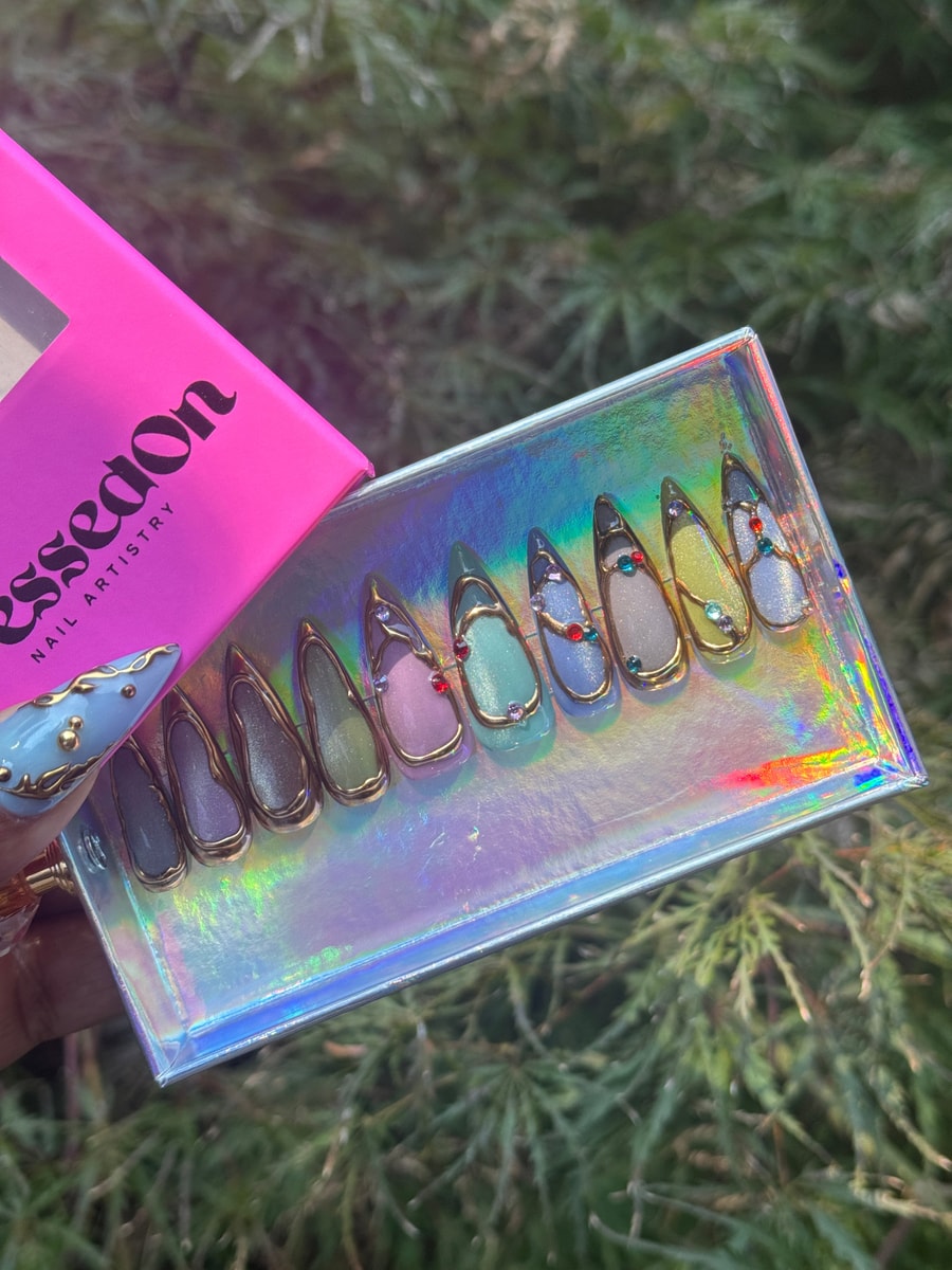 Assorted pastel-colored short press-on nails with gold outlines and gem decorations.