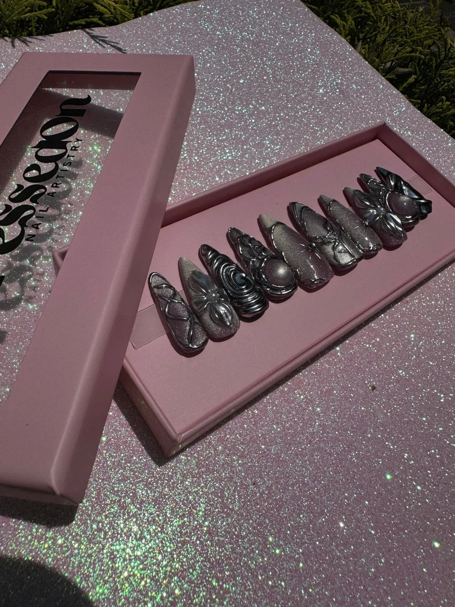 Medium chrome press-on nails featuring 3D sculptural silver decorations, including flower, swirl, and orb accents.