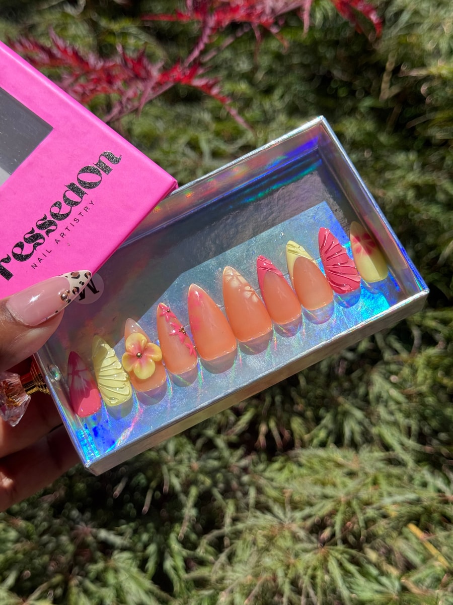 This set features short, almond-shaped press-on nails with a springtime vibe. The set includes peach, yellow, and pink tones, with floral and textured accents, plus a 3D flower.