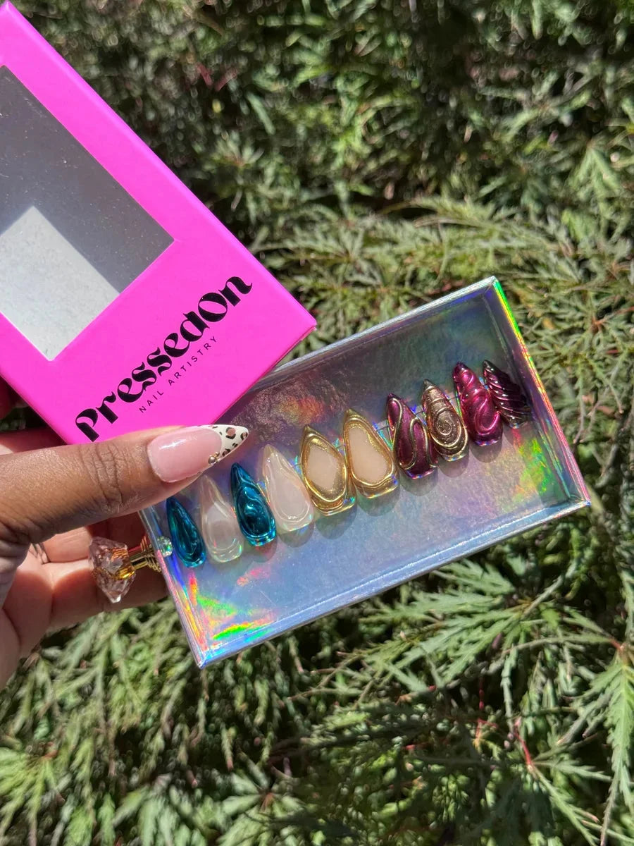 Set of short press-on nails with chrome and 3D designs. Colors include teal, clear with a gold frame, and purple.