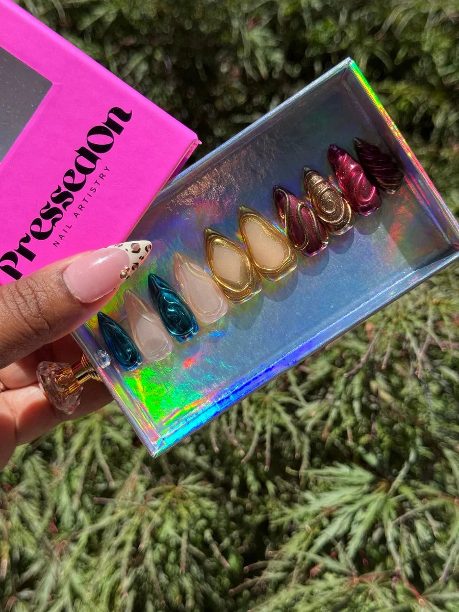 Set of short press-on nails with chrome finishes and 3D designs in an assortment of colors, including gold, pink, and teal.