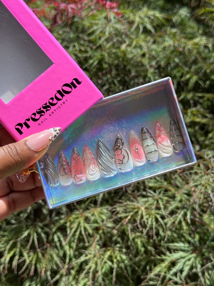 Medium length unicorn press-on nails are decorated with silver line art and butterfly accents, some with pink details.