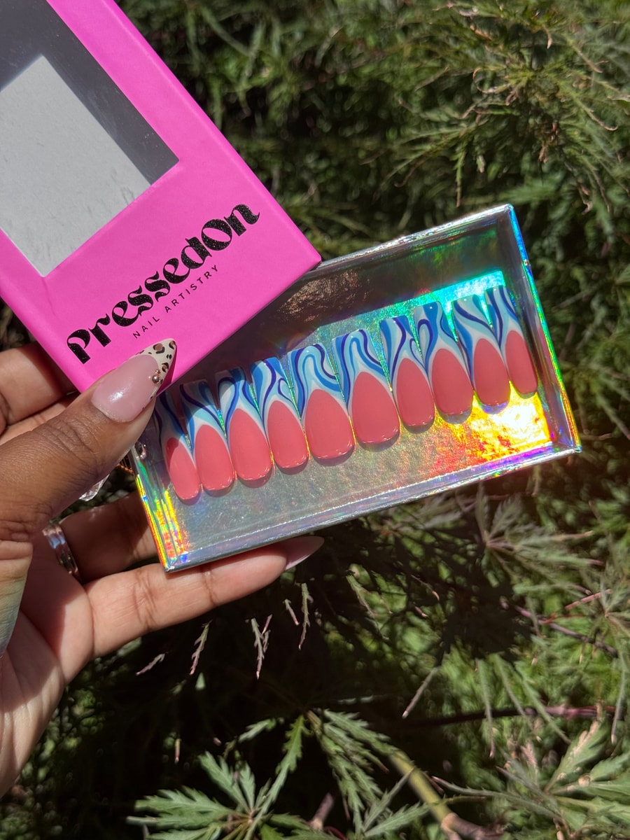 Coral medium-length press-on nails feature a unique wavy blue and white design at the tips.