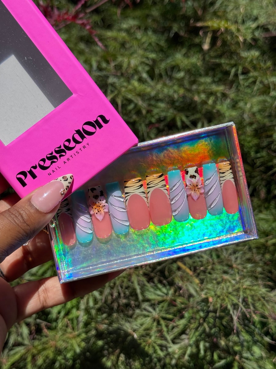 Medium-length press-on nails featuring zebra and cheetah prints, French tips, 3D flower embellishments, and pastel swirl designs.